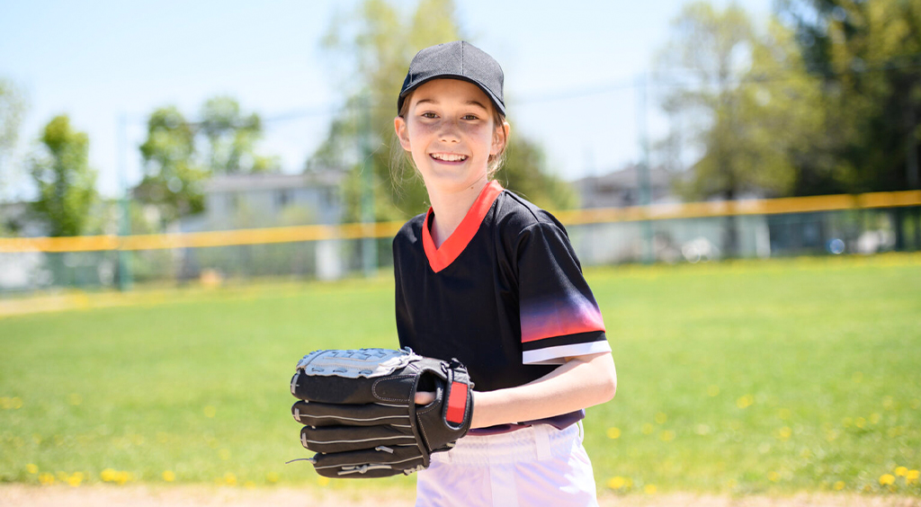 Young girl playing baseball on summer day