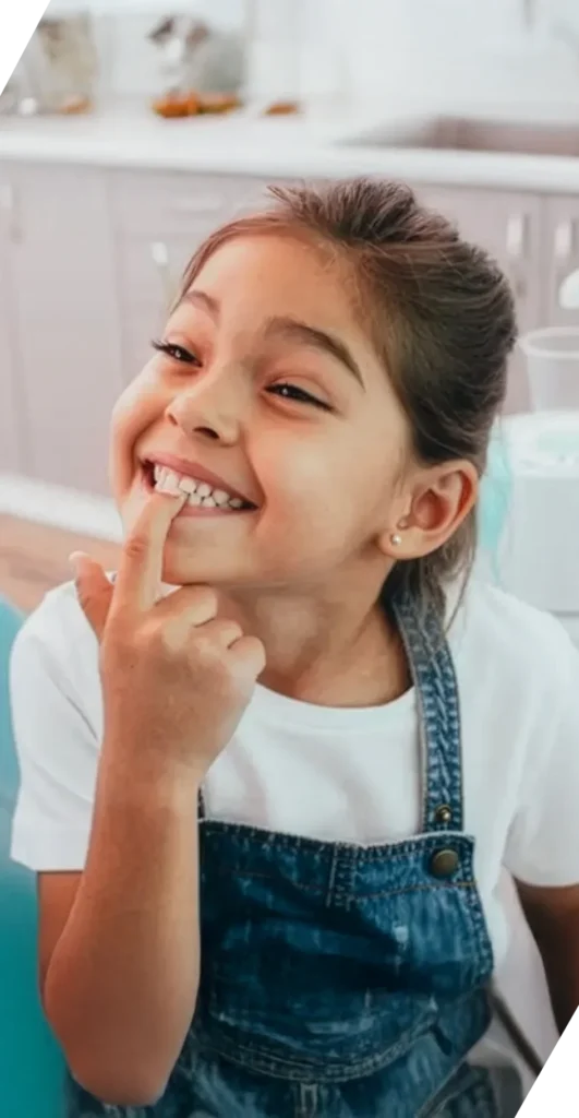 Young girl pointing at her teeth and smiling